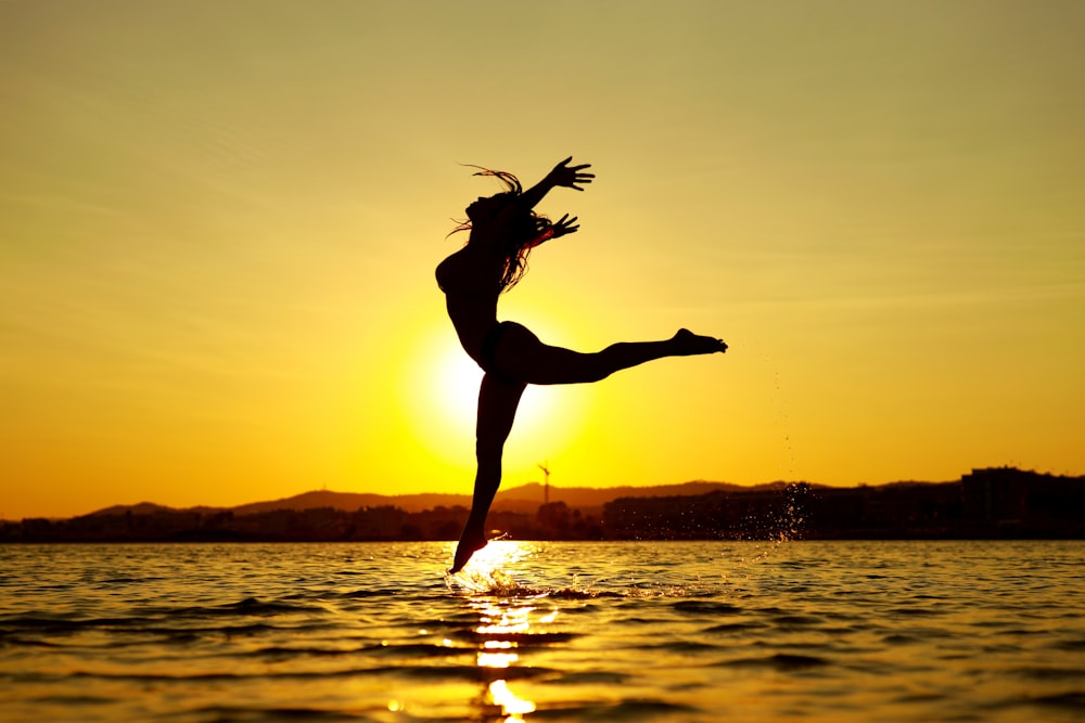 woman jumping on water during sunset