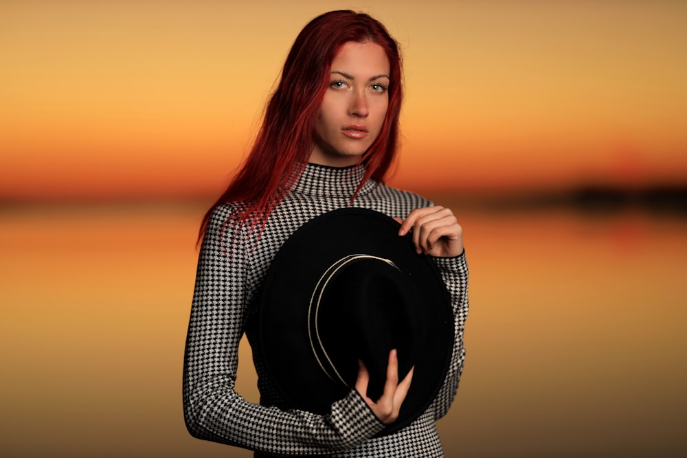 woman in black and white long sleeve shirt holding black hat