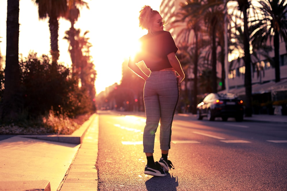 woman in white tank top and white pants walking on road during daytime