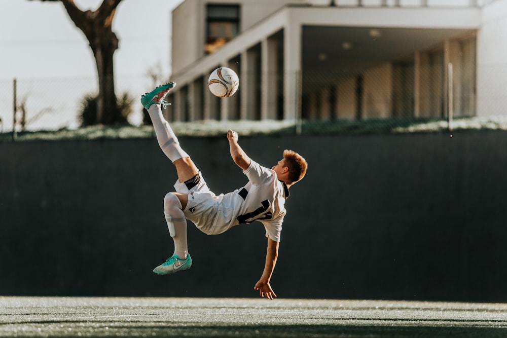 man in white and red jersey shirt and white shorts playing soccer