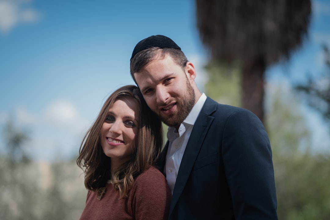 man in black suit jacket smiling beside woman in brown sweater