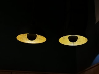 A contemporary pendant light in black with a warm yellow glow.