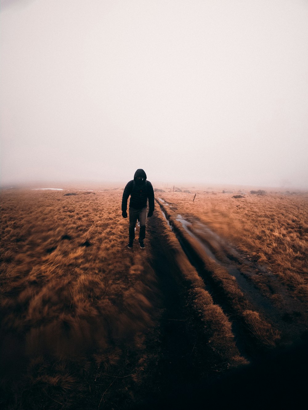 man in black jacket walking on brown sand during daytime