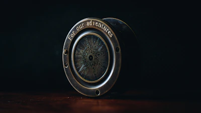 A golden compass resting on a black leather travel journal, symbolizing guidance and adventure.