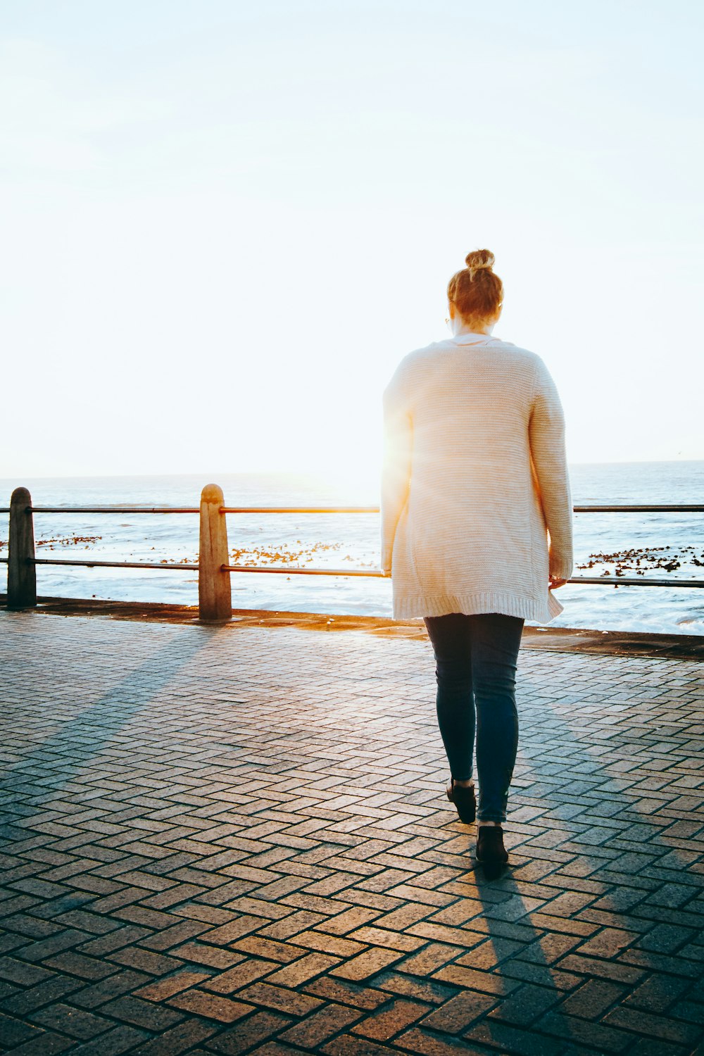 woman in white long sleeve shirt and black pants standing on dock during daytime