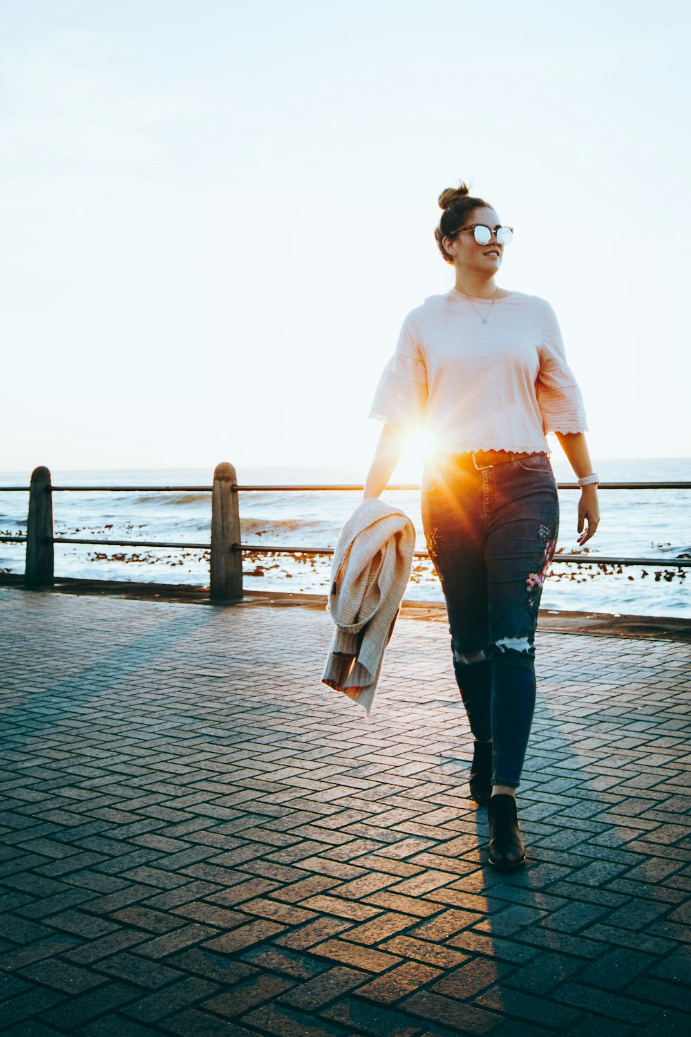 donna in camicia bianca a maniche lunghe e pantaloni neri in piedi sul molo durante il giorno