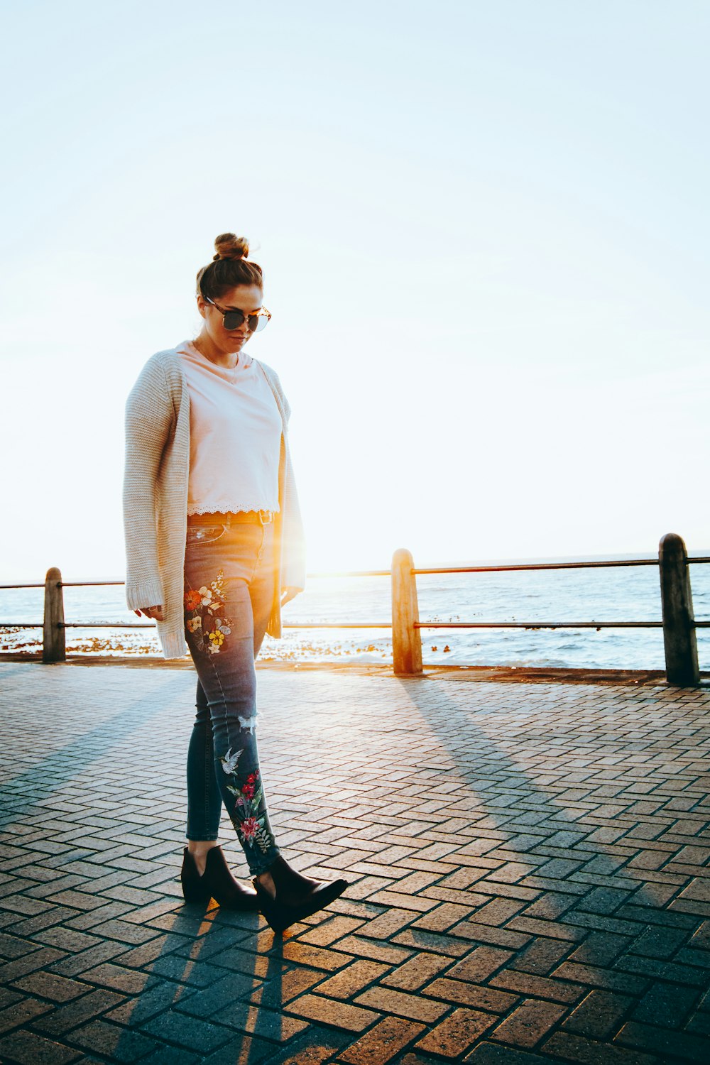 woman in white long sleeve shirt and blue denim jeans standing on dock during daytime