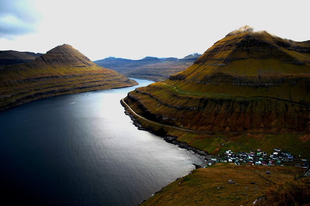 brown and green mountain beside river during daytime