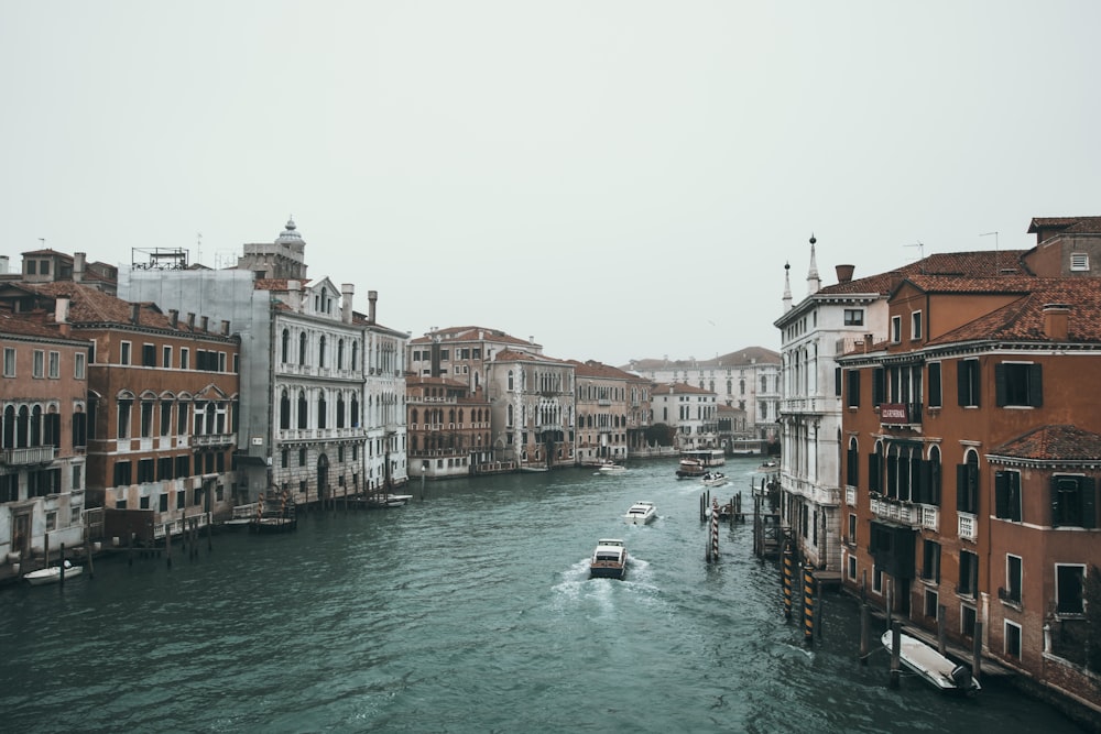 people riding on boat on river between buildings during daytime