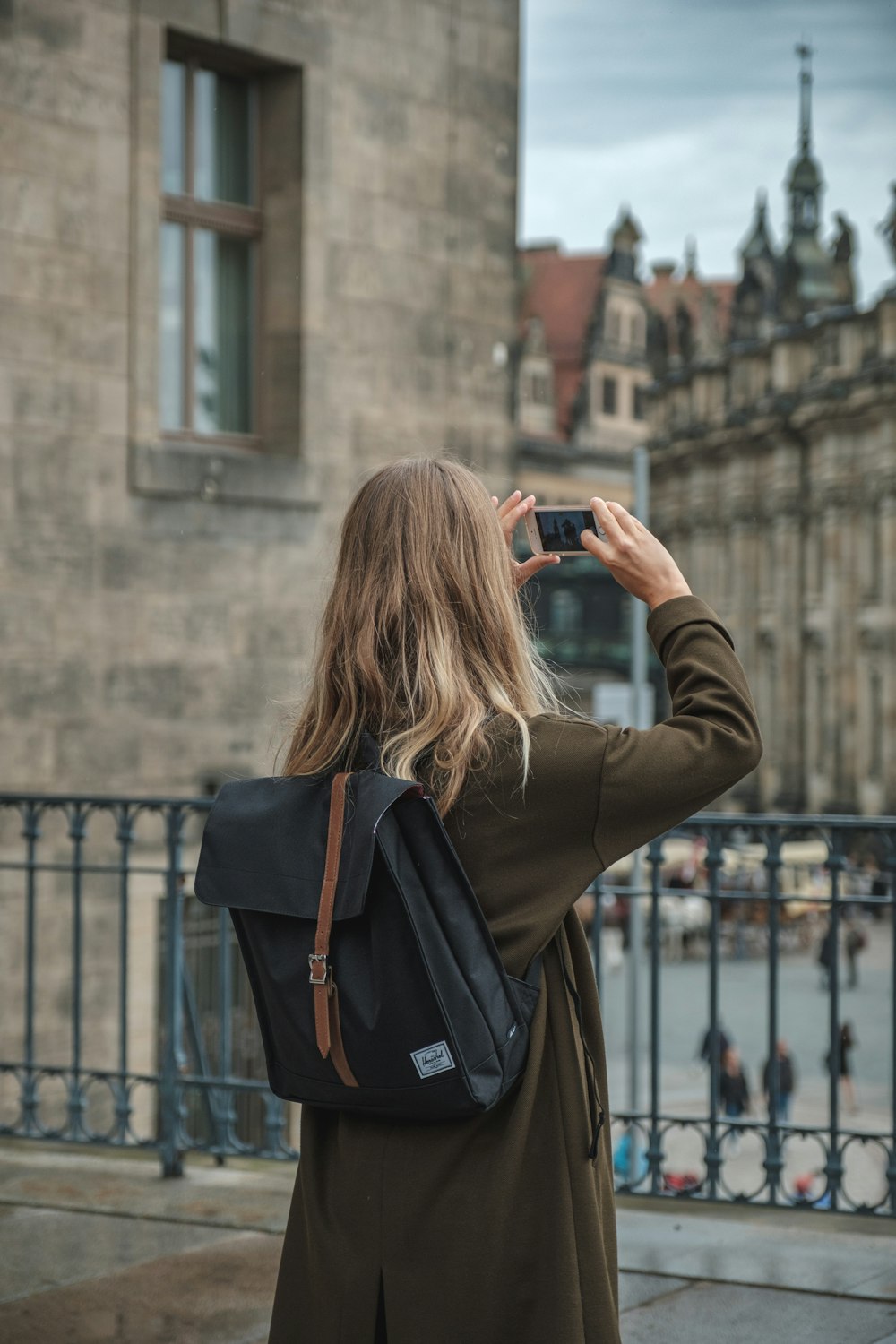 검은 DSLR 카메라를 사용하여 사진을 찍는 회색 재킷을 입은 여자