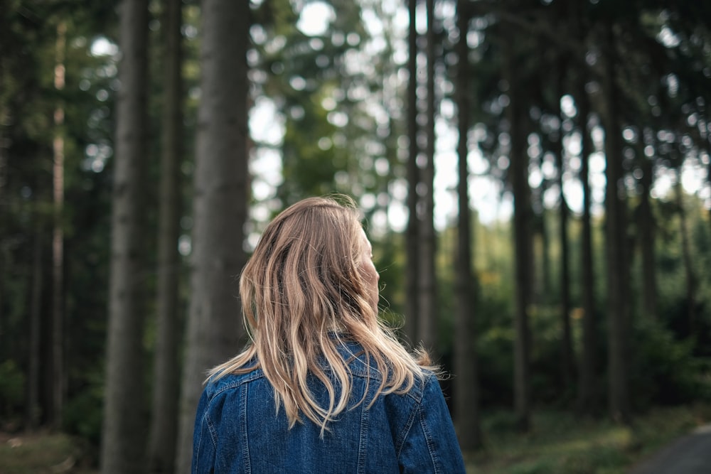 woman in blue denim jacket standing in forest during daytime
