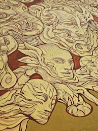 A large mural featuring intricately drawn faces and abstract forms. The art style is highly detailed with numerous swirling lines and patterns that merge and diverge. The expressions on the faces vary, conveying a sense of mystery and depth.