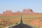 gray asphalt road between green grass field during daytime