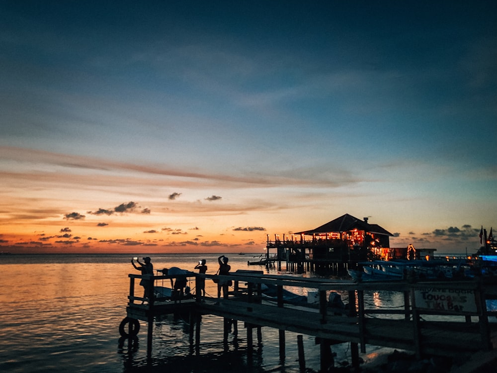 silhouette of people on dock during sunset