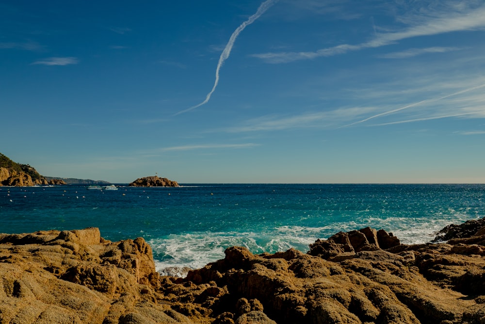 brown rock formation on sea under blue sky during daytime