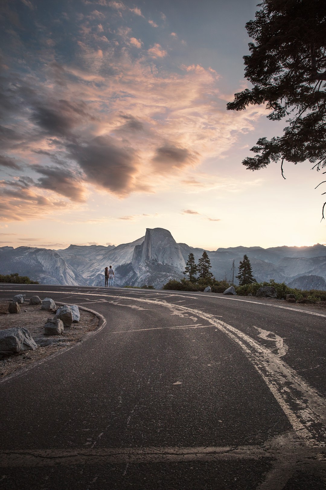 A couple standing the end of a long road during sunrise at Glacier Point in Yosemite National Park, California.

Explore more at explorehuper.com
