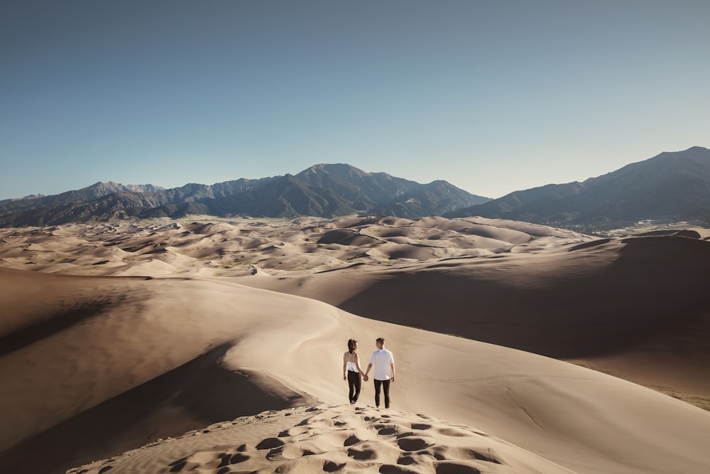 2 person walking on sand during daytime