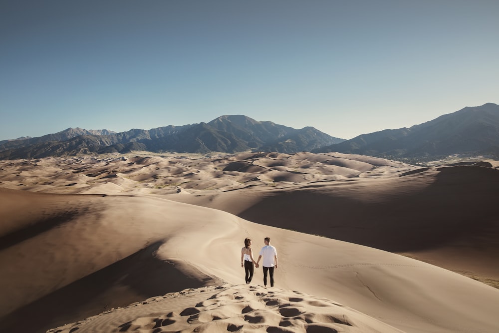 2 personas caminando sobre la arena durante el día