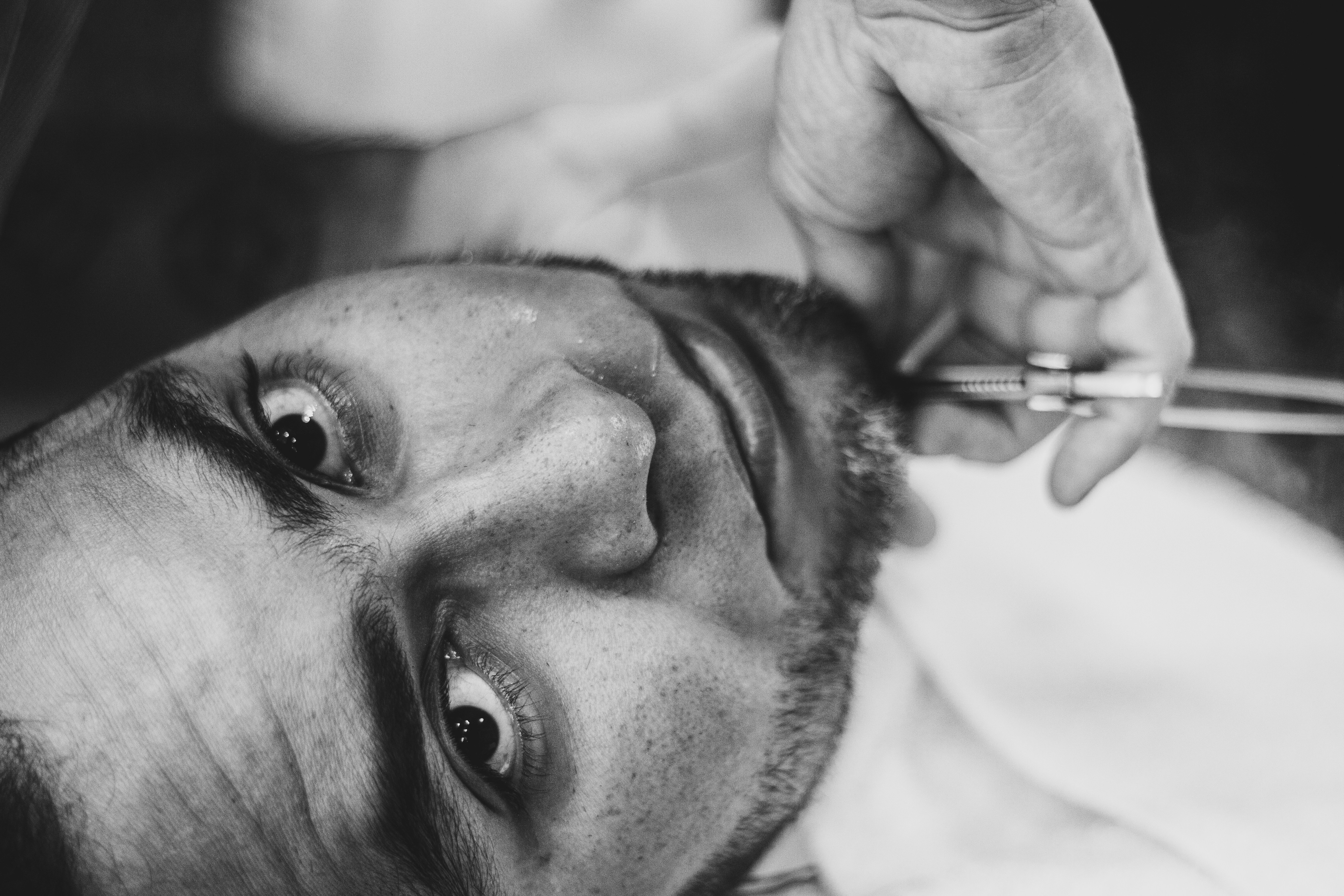A barber meticulously shaving a client's beard
