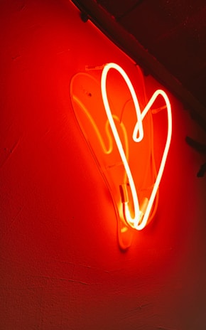 Colorful neon sign shaped like a vibrant heart glowing in a dim room