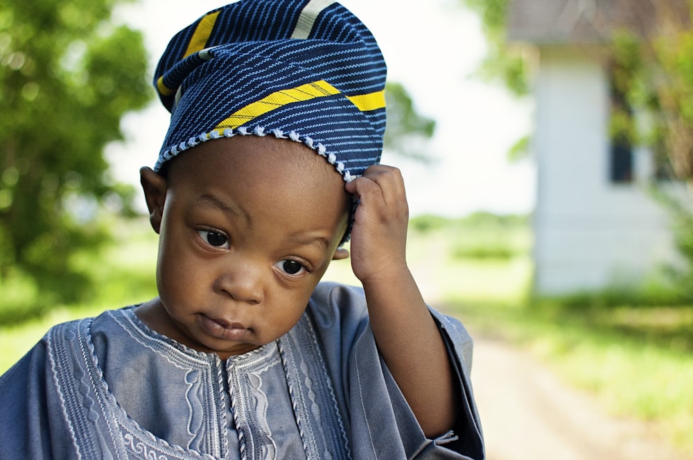 boy in blue and yellow hat and blue denim jacket