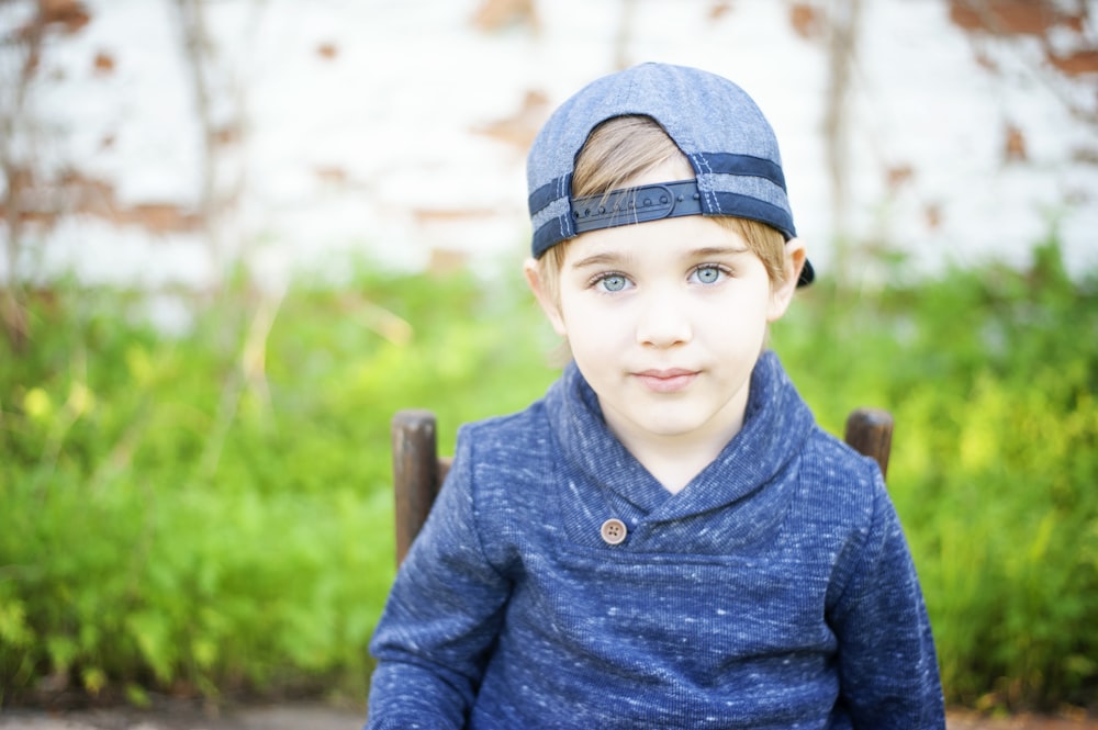 boy in blue knit sweater and blue denim cap