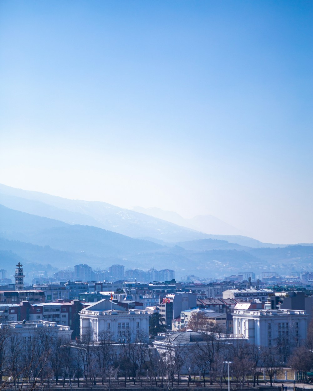 Stadtgebäude in der Nähe von Bergen unter blauem Himmel tagsüber