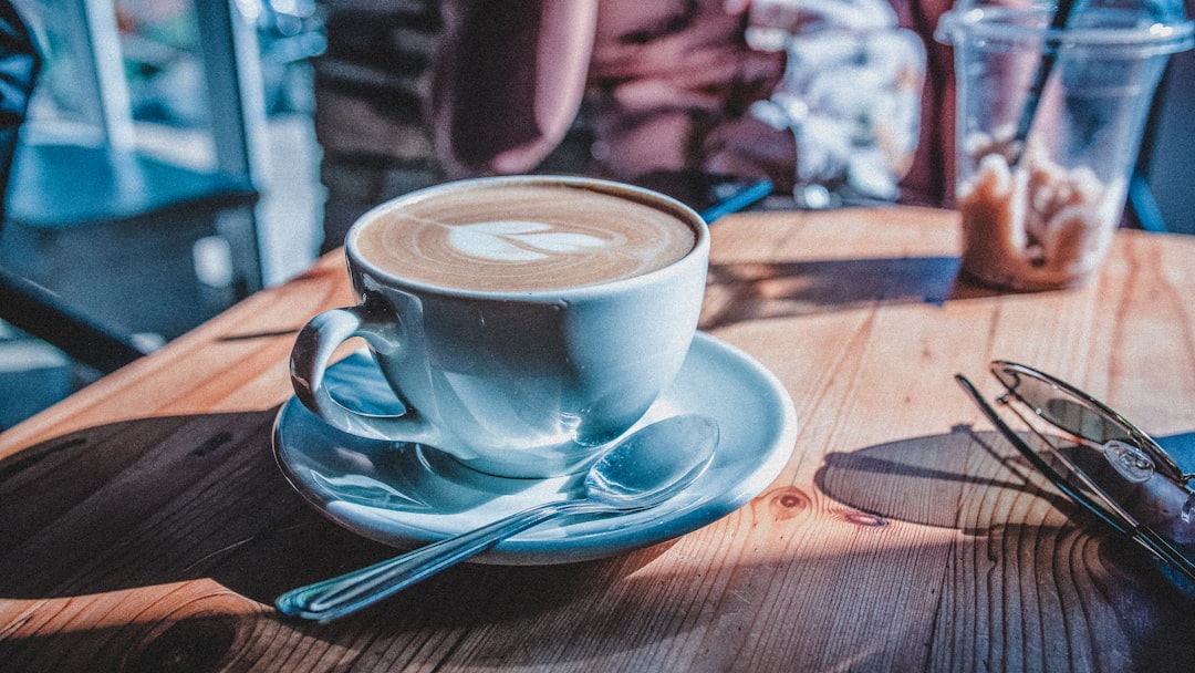 white ceramic cup with saucer on brown wooden table