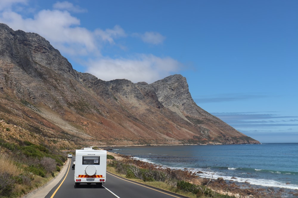 white van on road near body of water during daytime