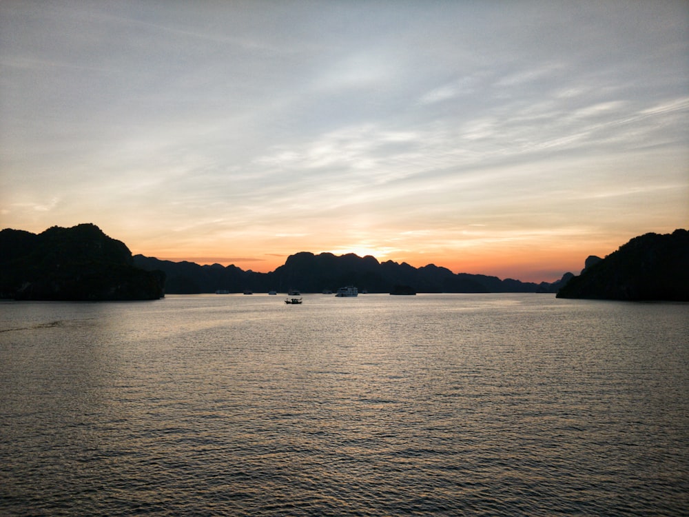 silhouette of mountain near body of water during sunset