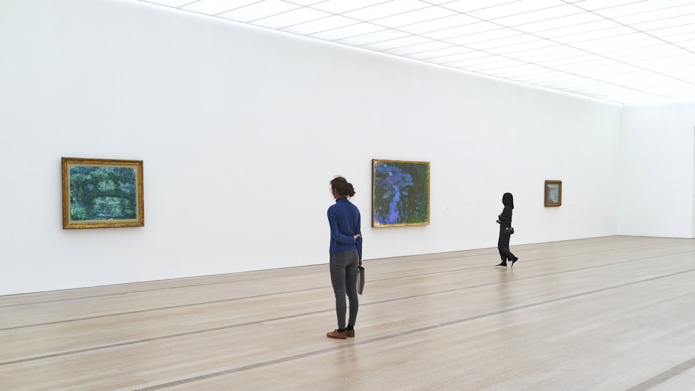 man in blue long sleeve shirt and black pants walking on brown wooden parquet floor