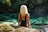woman in black tank top and blue shorts sitting on rock near body of water during