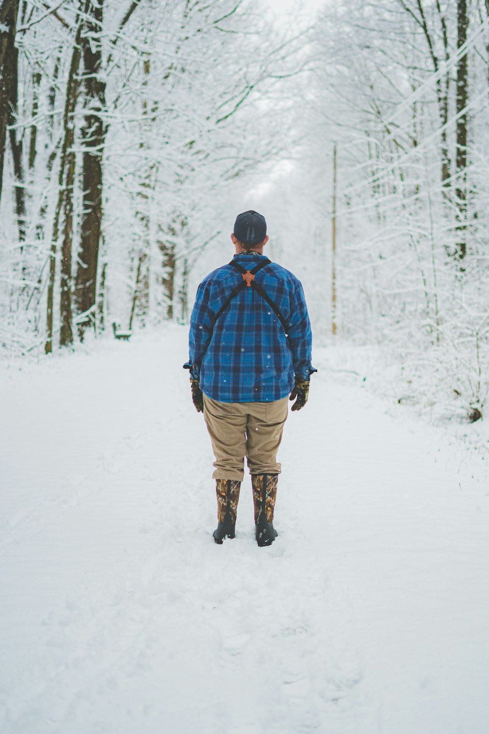 man in blue and red jacket and brown pants walking on snow covered ground during daytime