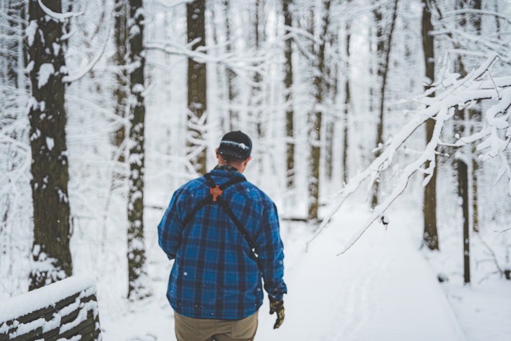 man in blue and red plaid dress shirt and brown pants standing on snow covered ground