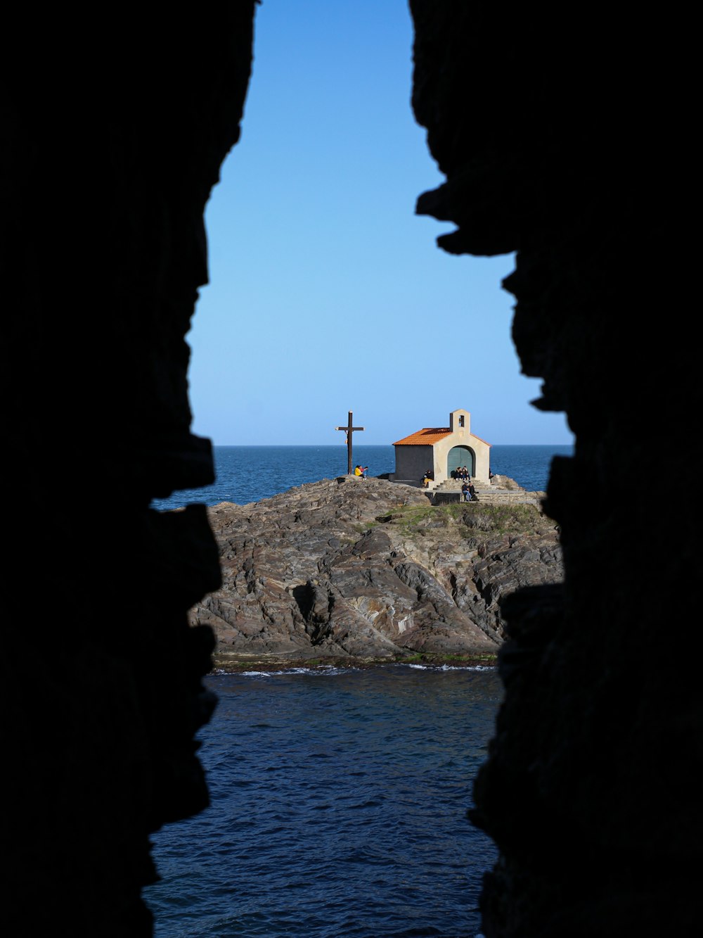 a view of a lighthouse through a hole in a rock wall