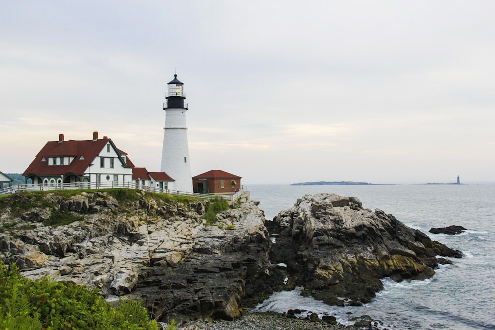 white and brown lighthouse on brown rocky mountain during daytime