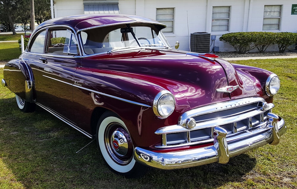 red classic car parked on green grass field during daytime