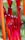Brightly colored glass sculptures with elongated, organic shapes in shades of vibrant red and orange. The reflective surface of the glass enhances the rich hues against a blurred outdoor background.