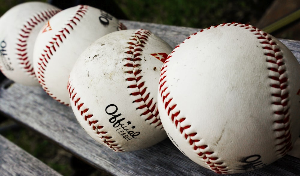 Pelota de béisbol blanca y roja sobre mesa de madera negra