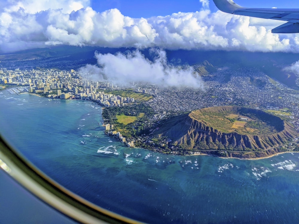 aerial view of green and brown island under blue sky and white clouds during daytime