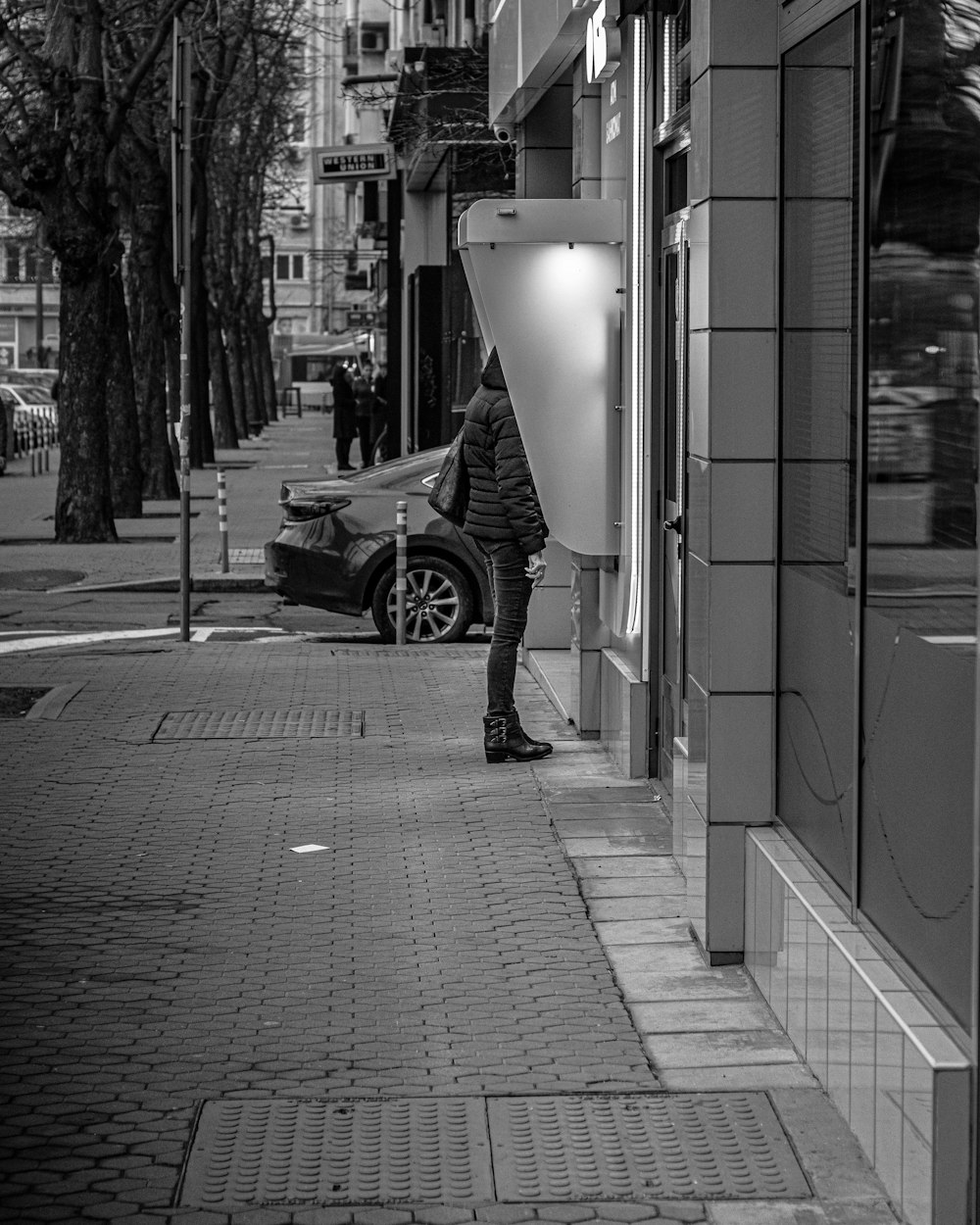 grayscale photo of man riding bicycle on sidewalk