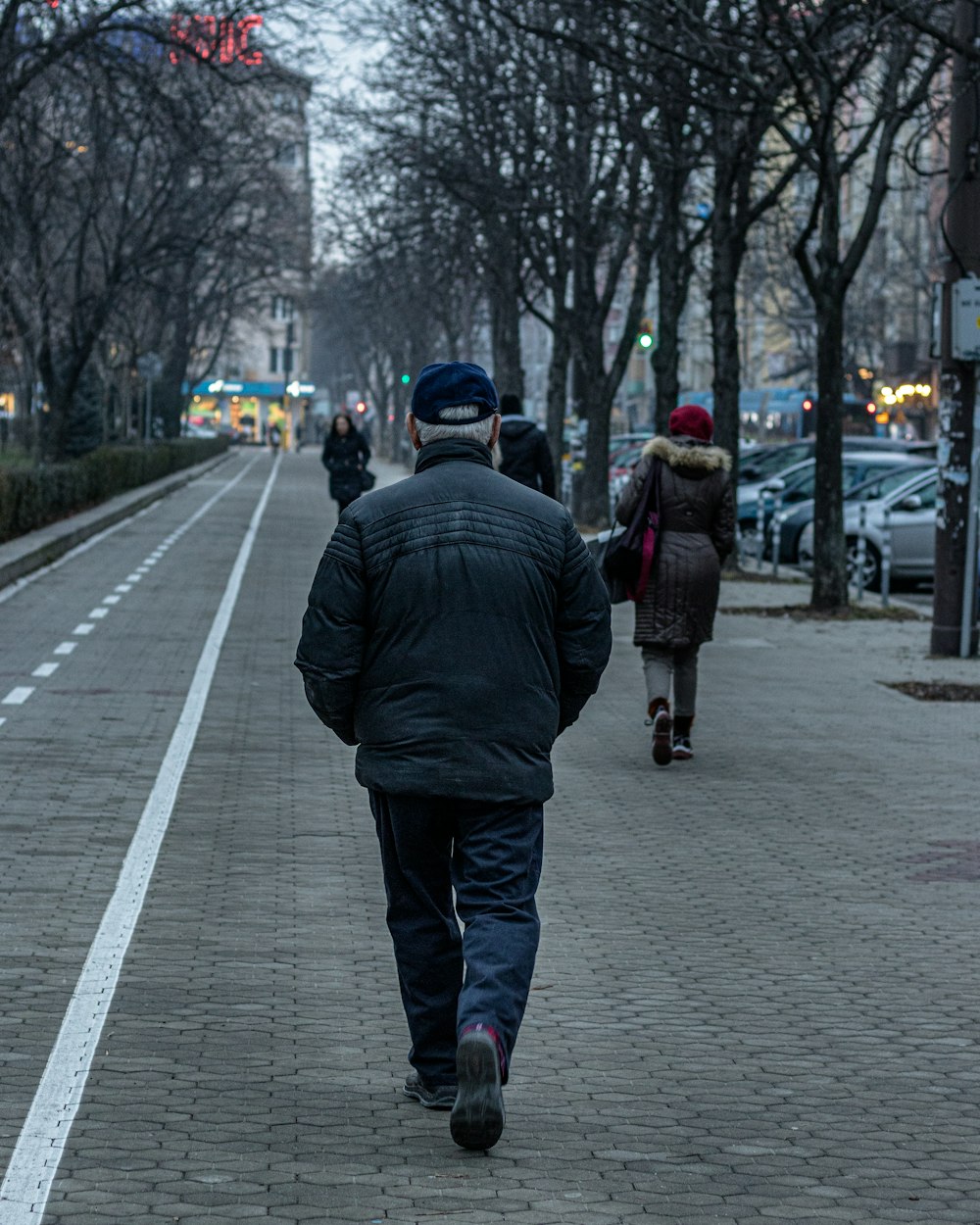 man in black jacket walking on sidewalk during daytime