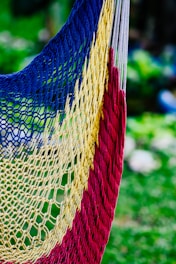 Close-up of vibrant Colombian woven hammocks hanging between trees in a lush landscape.