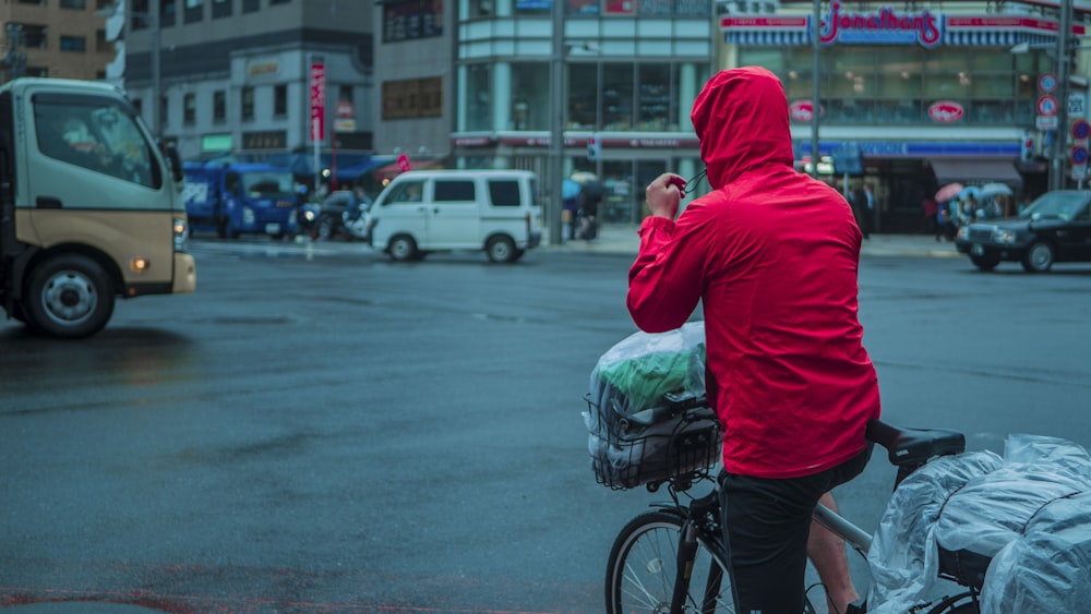 man in red hoodie and black shorts holding green plastic bag