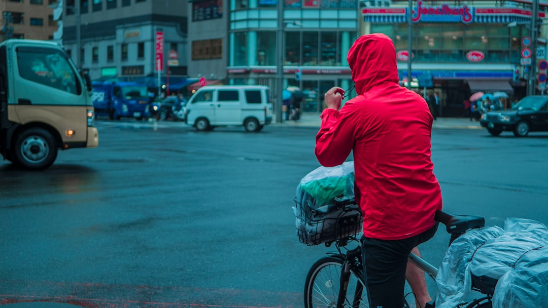 man in red hoodie and black shorts holding green plastic bag