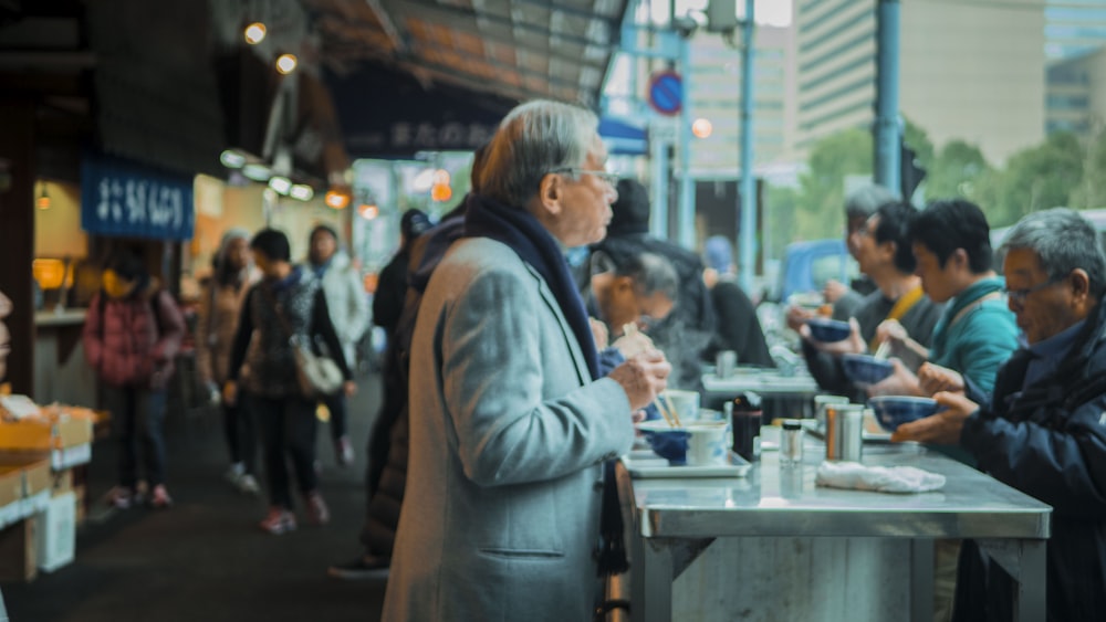 woman in gray coat standing near people during daytime