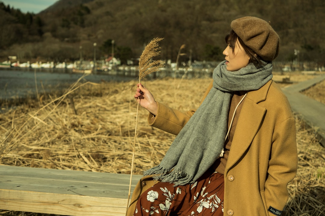 woman in brown coat holding brown stick