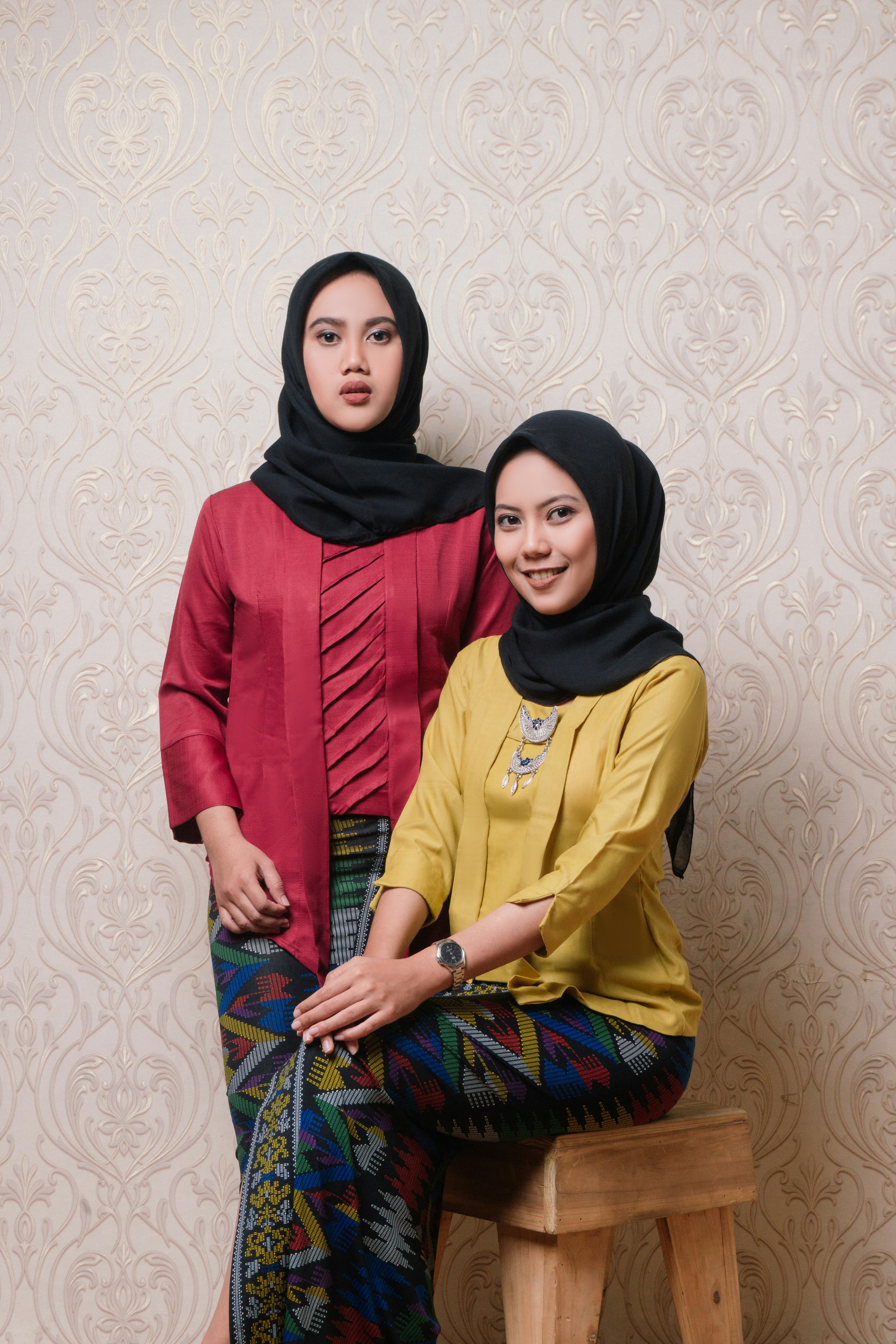 Wanita berjilbab merah berdiri di samping wanita berjilbab merah