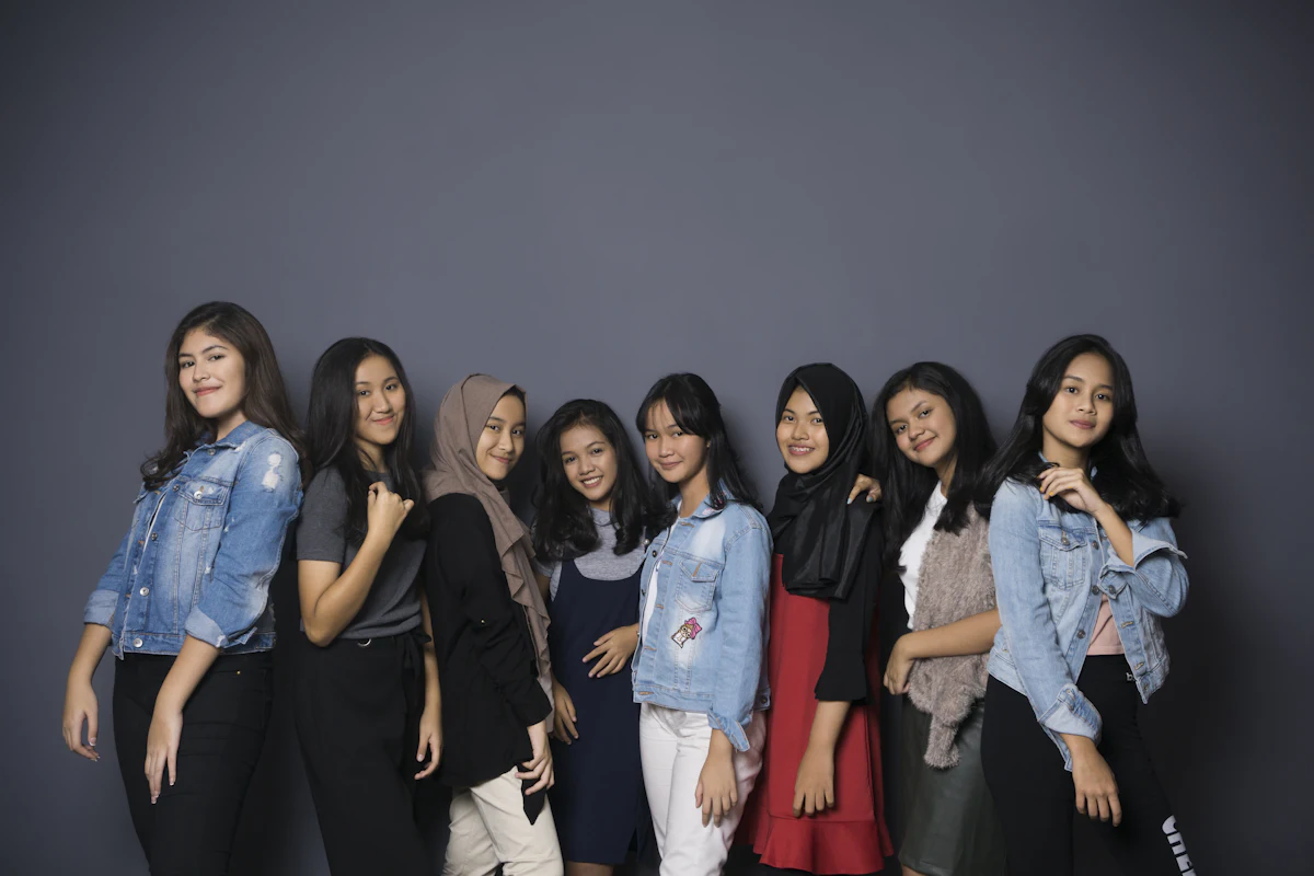 Sekelompok perempuan muda Indonesia berpose bersama di depan latar studio, beberapa memakai jaket denim serupa