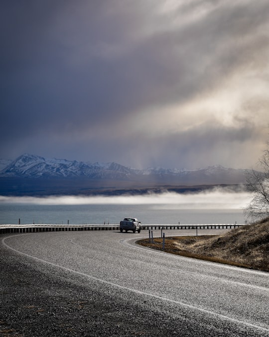 black car on road near body of water during daytime in Lake Tekapo New Zealand